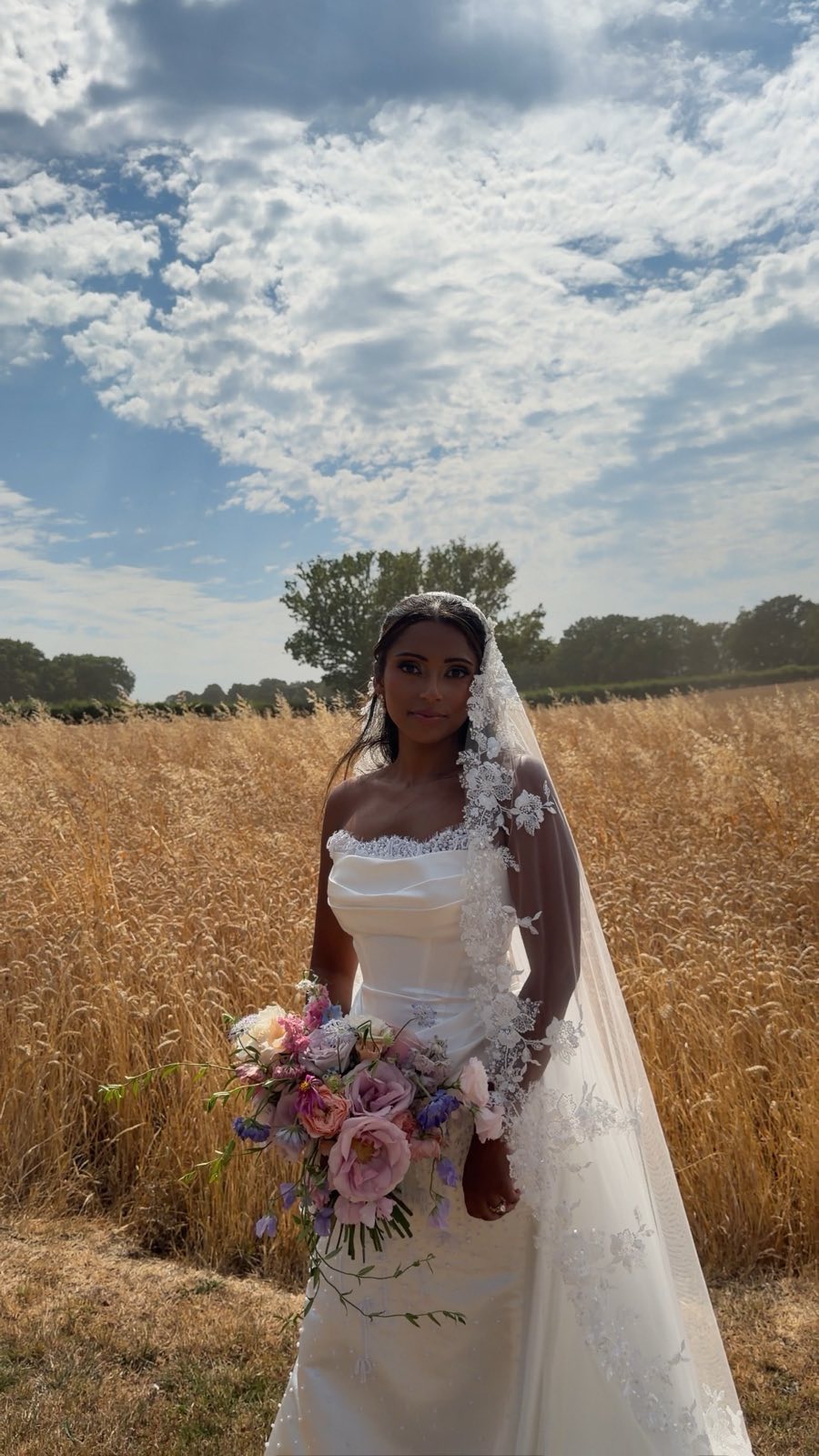 Bride holding her bouquet in a golden wheat field