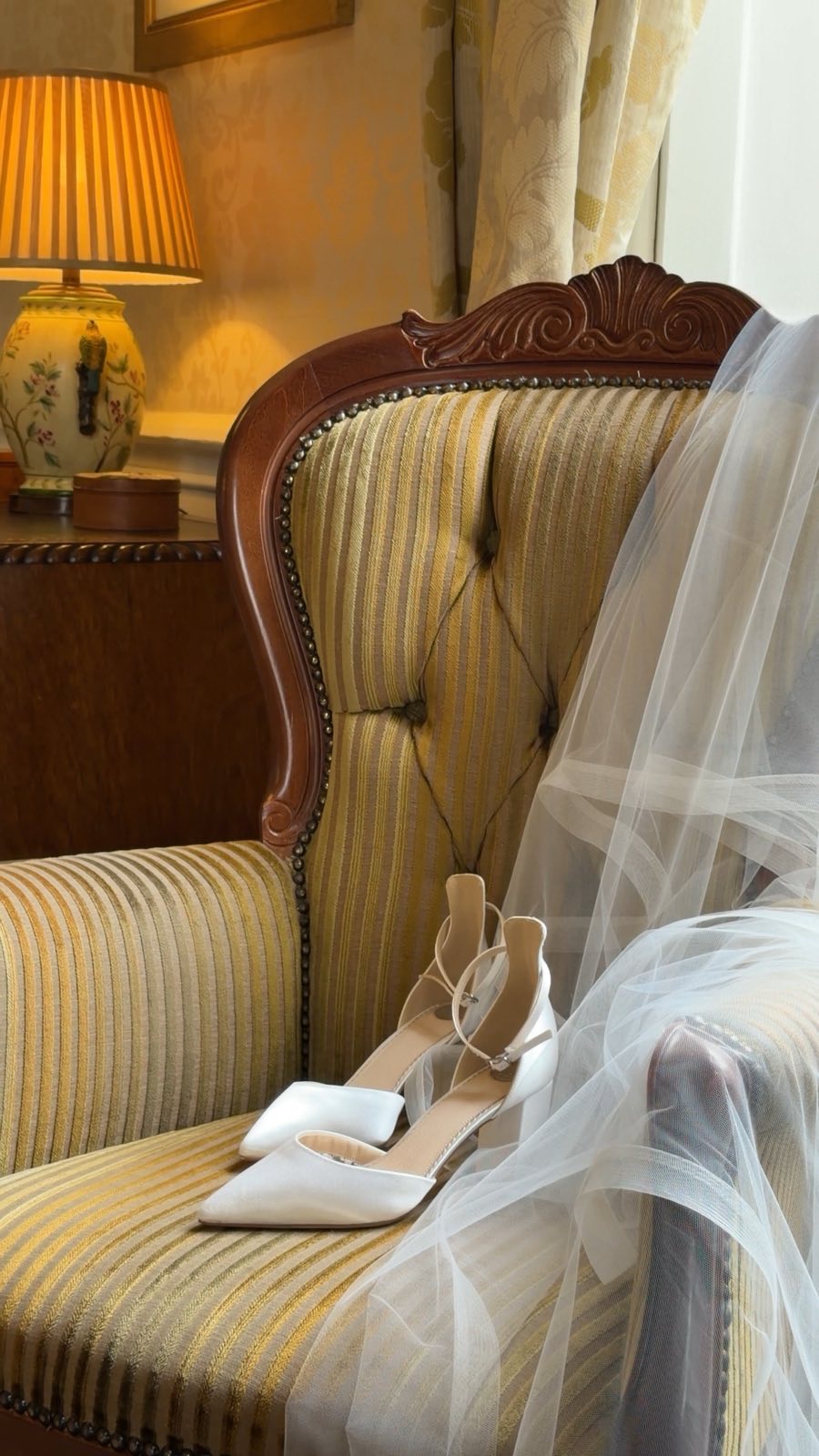 Bridal shoes and veil resting on a vintage armchair