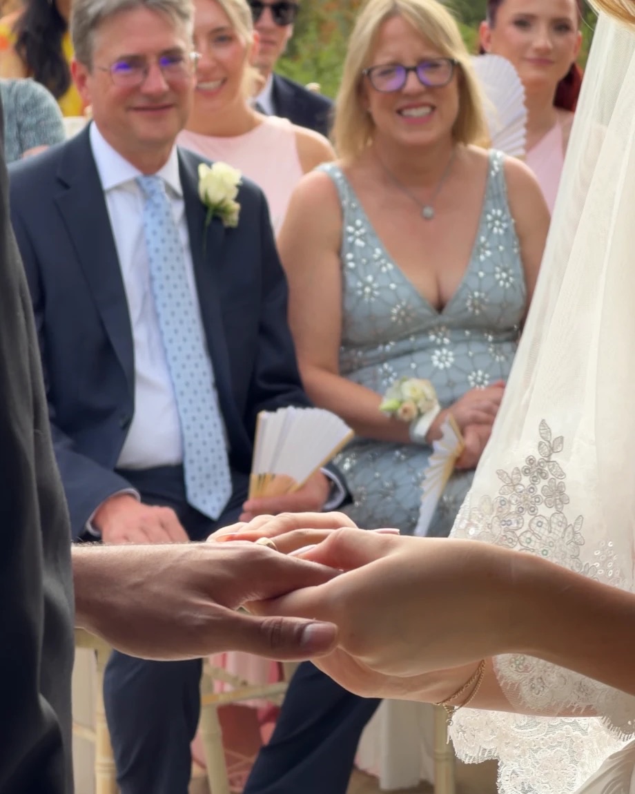 Ring exchange as the bride's family watches and smiles